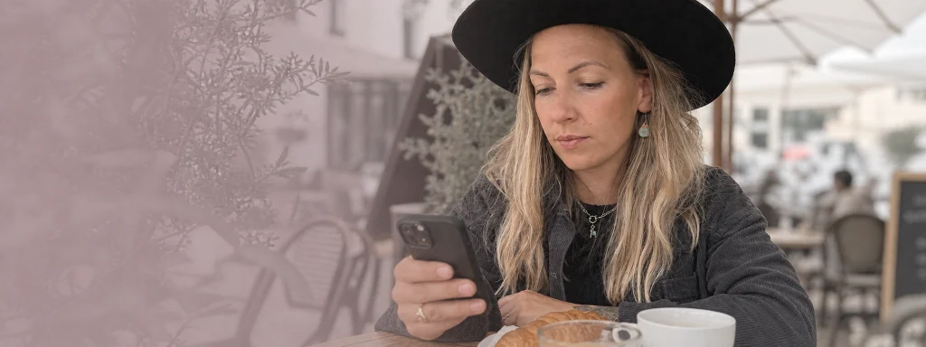Selina Klingebiel sitzt mit Smartphone im Café – jederzeit erreichbar für ihre Kund:innen